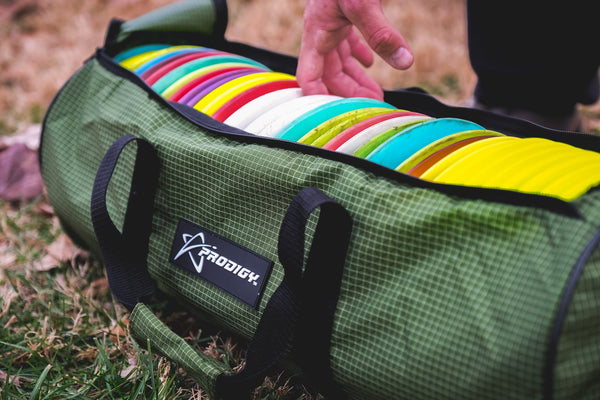 a hand picking a disc golf disc from a disc golf bag